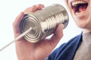 A man speaking into a can with a string attached to it